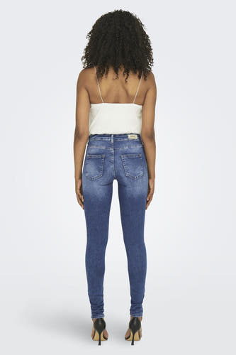 Jeans skinny en mid blue denim, de ONLY, avec un sac noir et des baskets blanches.