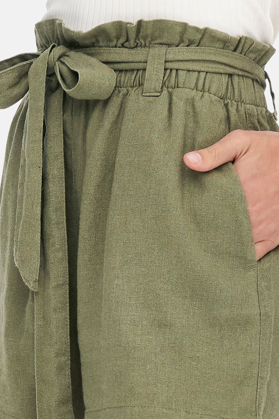 Olijfgroene linnen shorts met strikceintuur en hand in de zak.