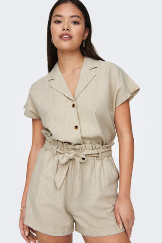 Vrouw in beige linnen blouse en shorts met riem.