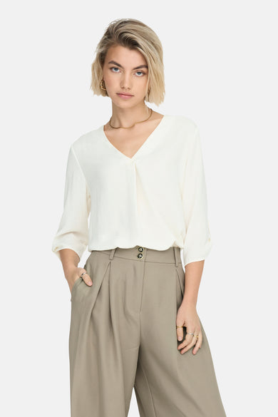 Blouse blanche à manches trois-quarts de JDY, portée avec un pantalon vert olive large et des sandales noires.