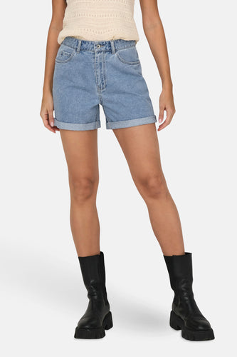 Vrouw in blauwe jeansshorts en zwarte laarzen.