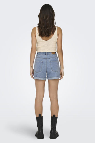 Vrouw van achteren, hemdje, jeansshort, zwarte laarzen.
