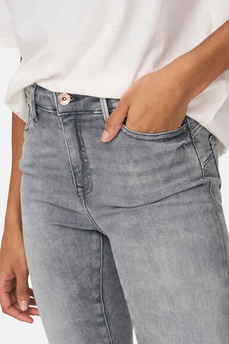 Jean skinny en denim gris clair d'ONLY, avec une main dans la poche et un t-shirt blanc.