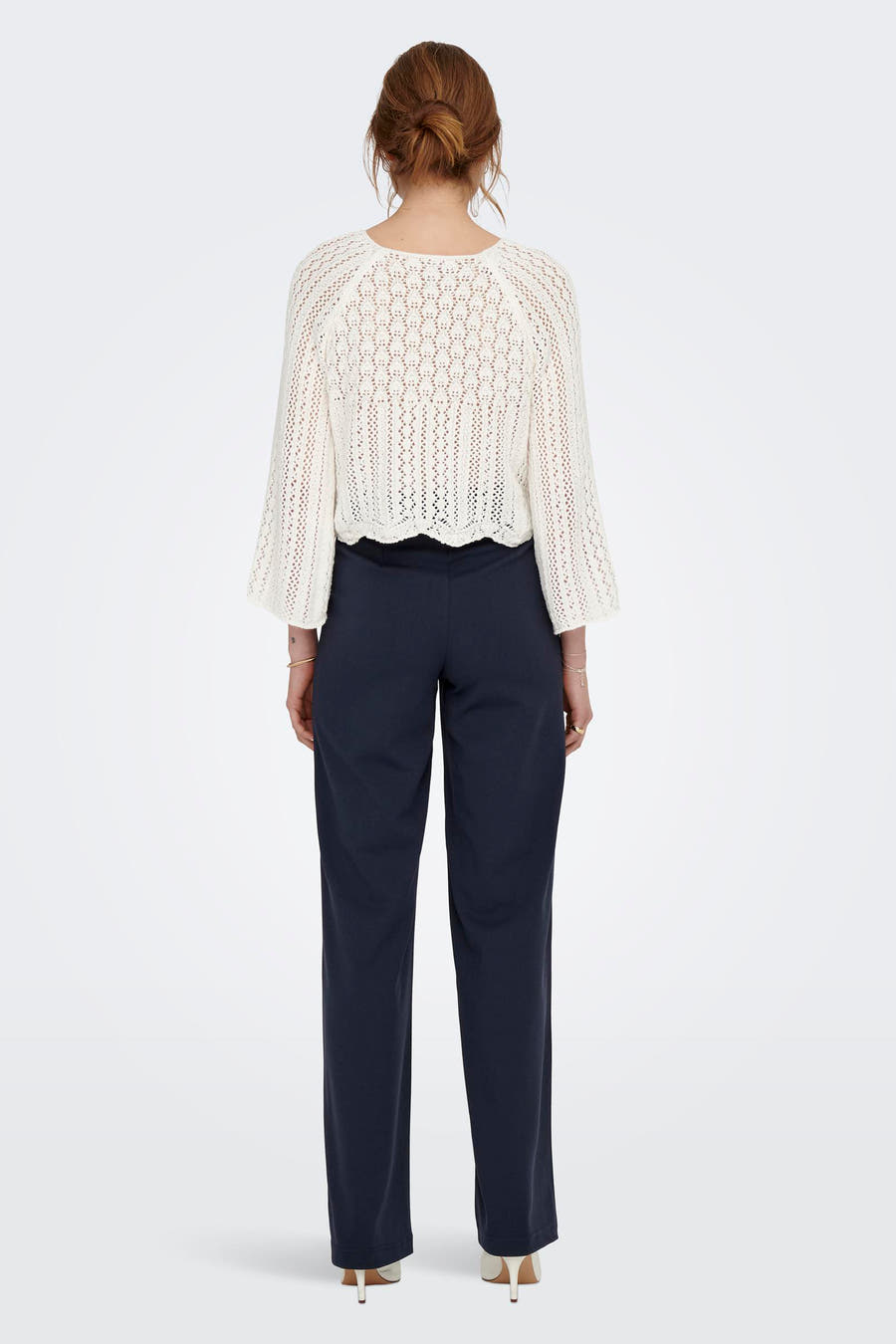 Cardigan écru d'ONLY, avec un tricot ajouré et des manches longues, combiné avec un pantalon sombre et des talons.