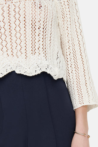 Gebroken wit gehaakt vest op marineblauwe broek.