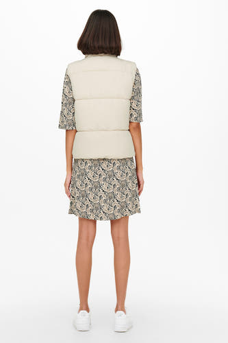 Gilet écru de JDY, associé à une robe fleurie et des baskets blanches.
