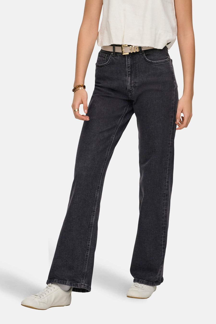 Jean large gris foncé de ONLY, avec une ceinture beige et des baskets blanches.