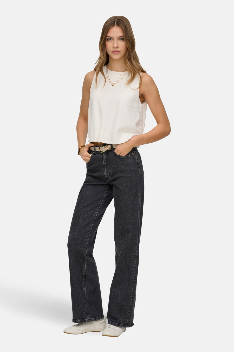 Jeans ample gris foncé d'ONLY, combiné avec un haut sans manches, des colliers dorés, un bracelet et des chaussures claires.