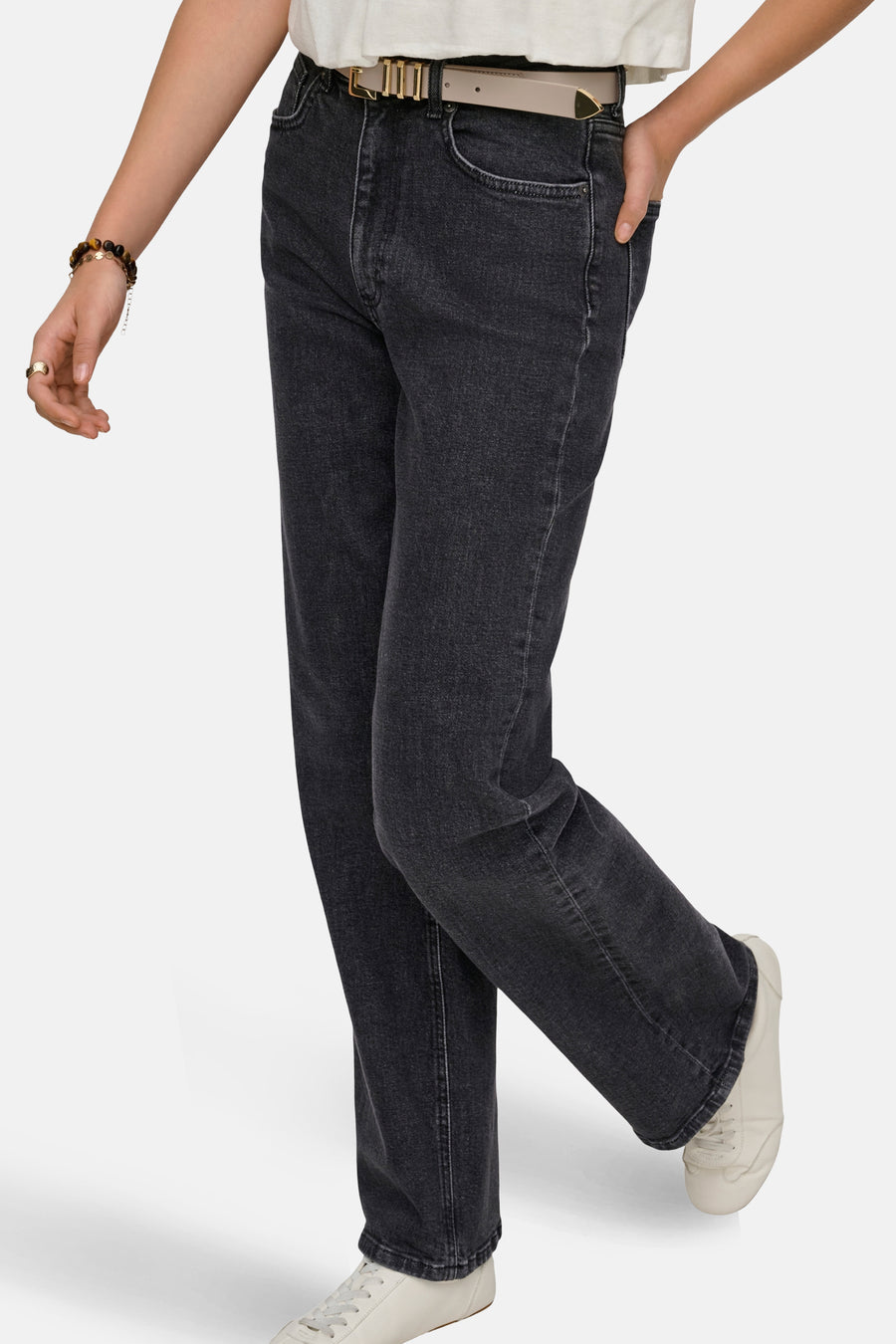 Jean large gris foncé de ONLY, avec une ceinture beige et des baskets blanches.