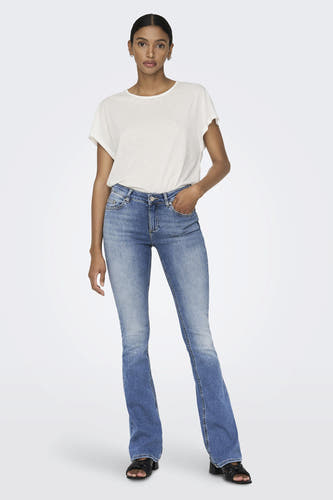 Uitlopende jeans van lichtblauw denim van ONLY, gedragen met een wit T-shirt en zwarte sandalen met hak.
