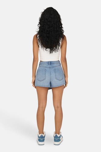 Short de denim bleu clair d'ONLY, vu de l'arrière, avec une chemise blanche et des baskets bleues et blanches.