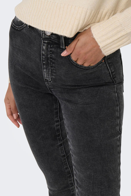 Jean skinny gris foncé de ONLY® avec des détails délavés subtils, coupe ajustée et poches visibles, porté avec un pull crème.
