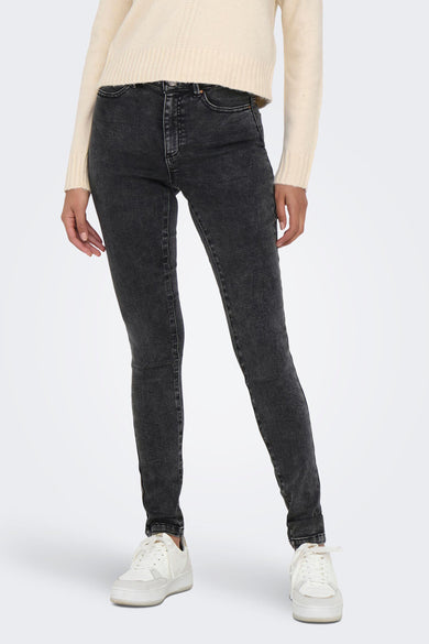 Jean skinny gris foncé de ONLY®, avec des détails légèrement délavés, une coupe ajustée et un style classique à cinq poches, porté avec un pull crème et des baskets blanches.