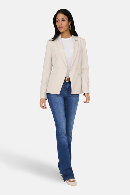 Jean flared bleu foncé d'ONLY, combiné avec une ceinture et un blazer de couleur crème.