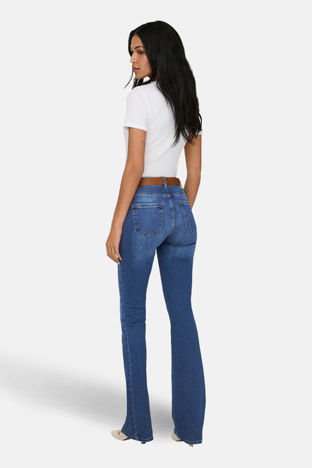 Jean flared bleu foncé d'ONLY, avec ceinture marron et haut blanc, vu de dos.