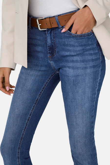 Jean flared bleu foncé d'ONLY, avec ceinture marron et main dans la poche.