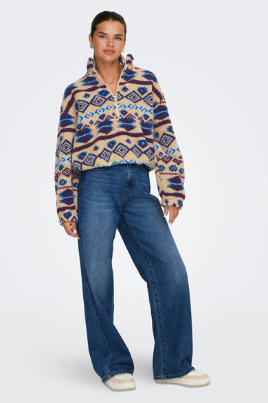 Mouton beige d'ONLY avec un motif bleu et bordeaux, combiné à des jeans et des baskets.