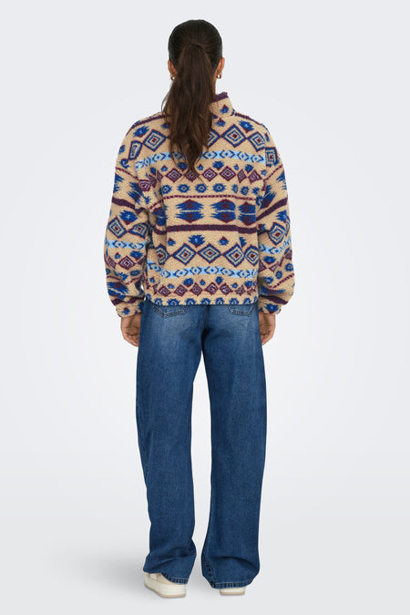 Mouton beige de ONLY, avec un motif ethnique frappant, porté avec des jeans larges et des chaussures crème.