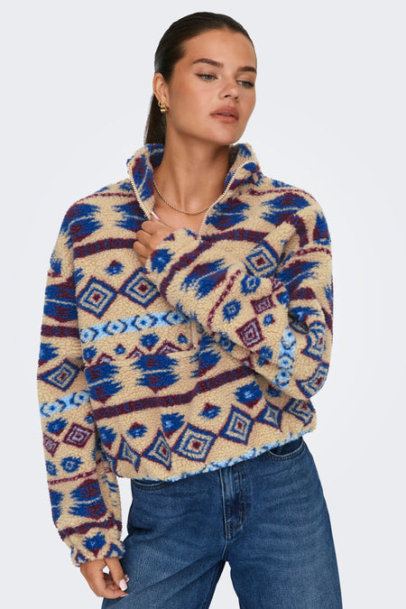 Mouton beige ONLY avec un motif graphique et une fermeture à glissière courte, porté avec un jean.