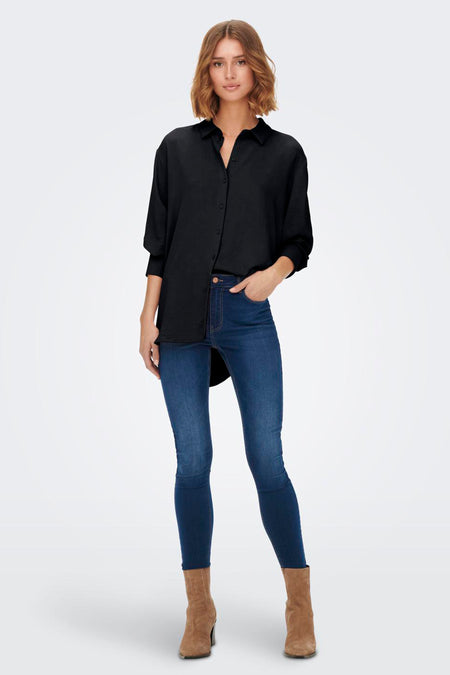 Chemise noire à manches longues de JDY, portée avec un jean bleu et des bottes marron.