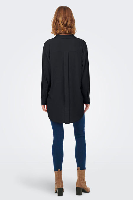 Chemise noire à manches longues de JDY, avec des plis dans le dos, portée avec un jean foncé et des bottines en daim.