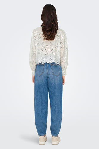 Chemise blanche à manches longues de ONLY, avec des détails ajourés et portée avec un jeans bleu.
