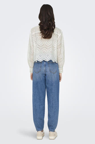 Chemise blanche à manches longues de ONLY®, avec un motif ajouré et portée avec des jeans bleus et des baskets crème.