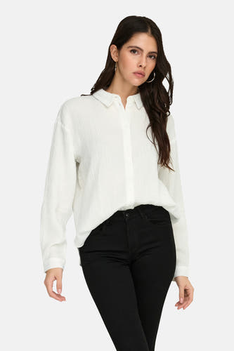 Chemise blanche à manches longues de JDY, avec une texture fine et portée avec un pantalon noir et des chaussures noires.