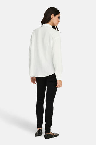 Chemise blanche à manches longues de JDY, avec une texture tissée et portée avec un pantalon et des chaussures noirs.