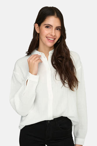 Chemise blanche à manches longues de JDY, avec fermeture boutonnée et portée avec un pantalon noir.