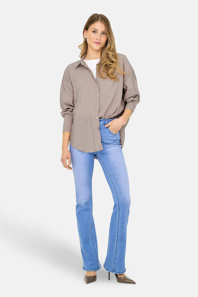 Chemise beige à longues manches de ONLY, portée avec un T-shirt blanc et des jeans bleus.
