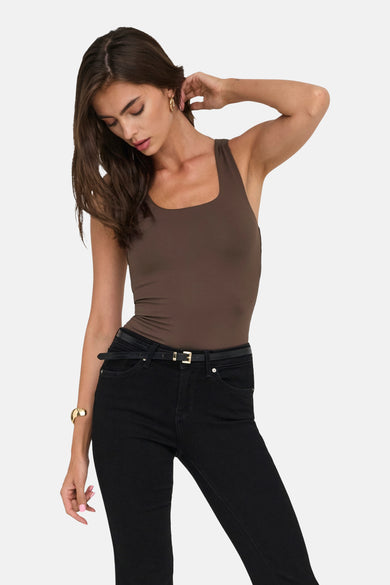 T-shirt marron avec des bandes de spaghetti d'ONLY, associé à des jeans noirs et une fine ceinture.