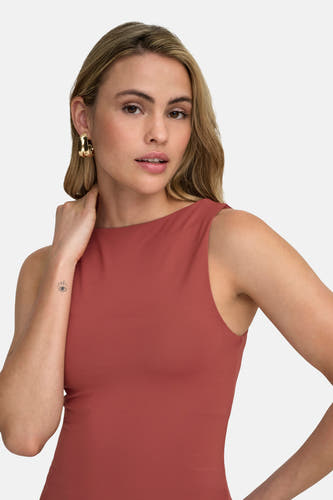 Haut rouge à fines bretelles de ONLY®, avec boucles d'oreilles dorées et un tatouage sur l'avant-bras.