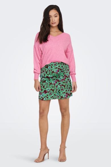 Groene korte rok van ONLY, met bloemenprint en gedragen met een roze trui en hakken.
