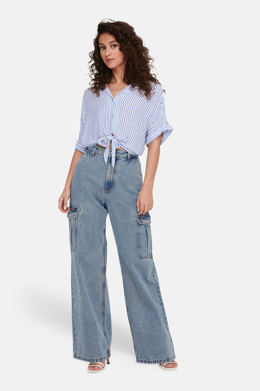 Wit hemd met korte mouwen van ONLY® met blauwe strepen, aan de voorkant geknoopt, gecombineerd met wijde jeans en witte sandalen.