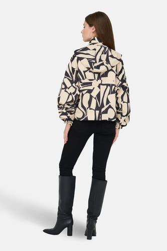 Manteau beige court de ONLY, avec un motif abstrait noir, associé à une jupe no et des des bottes.