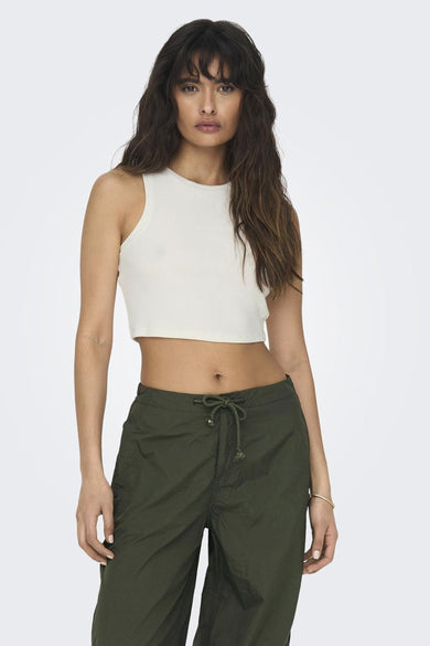 T-shirt écru sans manches de ONLY®, porté avec un pantalon vert et des chaussures blanches.