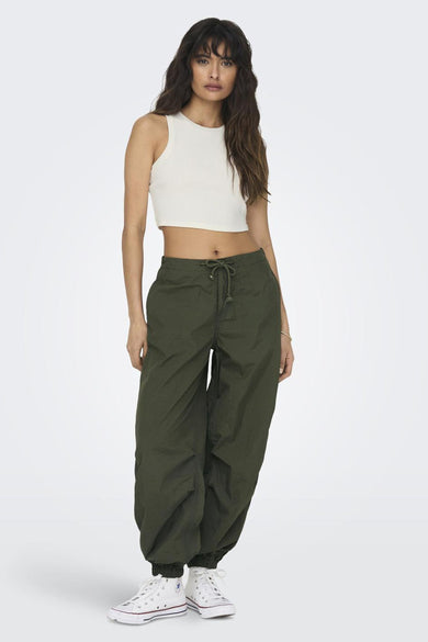 Ecru top zonder mouwen van ONLY, gedragen met een olijfgroene broek en witte sneakers.
