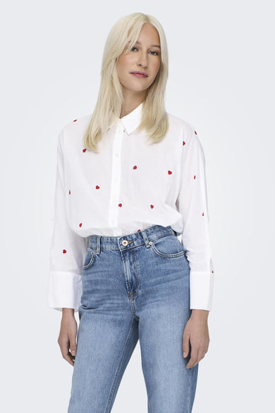 Chemise blanche à manches longues de ONLY, avec broderie citron, portée avec un jean bleu marine.