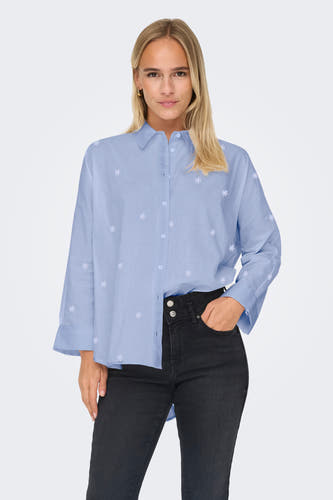 Chemise bleue à manches longues de ONLY, avec motif floral subtil et portée avec un jean noir.