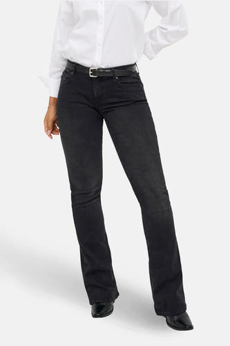 Jean flare noir de ONLY, avec une main dans la poche arrière et une blouse blanche.