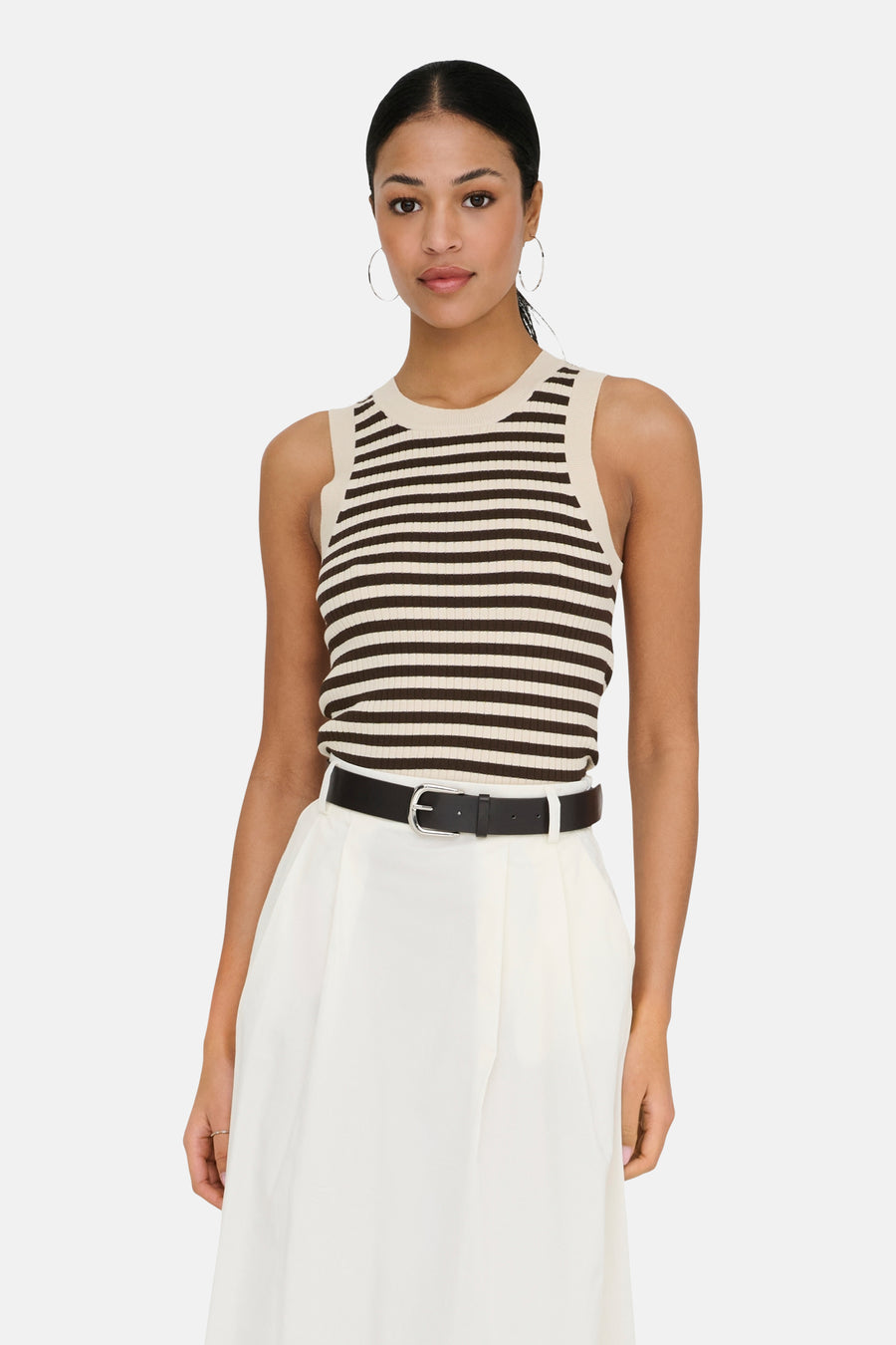Haut rayé sans manches en beige et marron foncé de JDY, combiné avec une jupe midi blanche et des chaussures Mary Jane noires.
