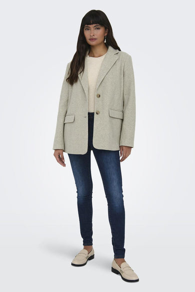 Manteau court beige ONLY, avec des manches longues, porté avec des jeans foncés et des loafers beige.