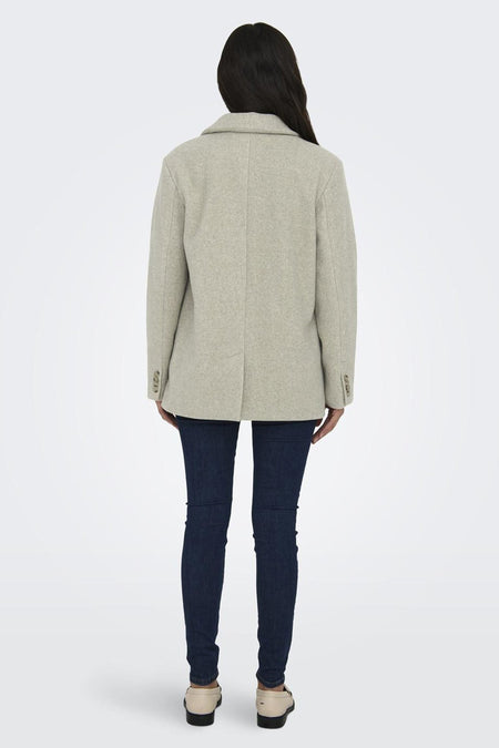 Manteau court beige d'ONLY, avec fermeture à boutons, porté avec un jeans foncé et des chaussures crème.