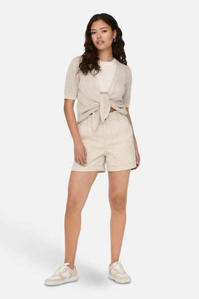 Beige vest van JDY, geknoopt aan de voorkant, gedragen over een wit T-shirt met bijpassende korte broek en sneakers.