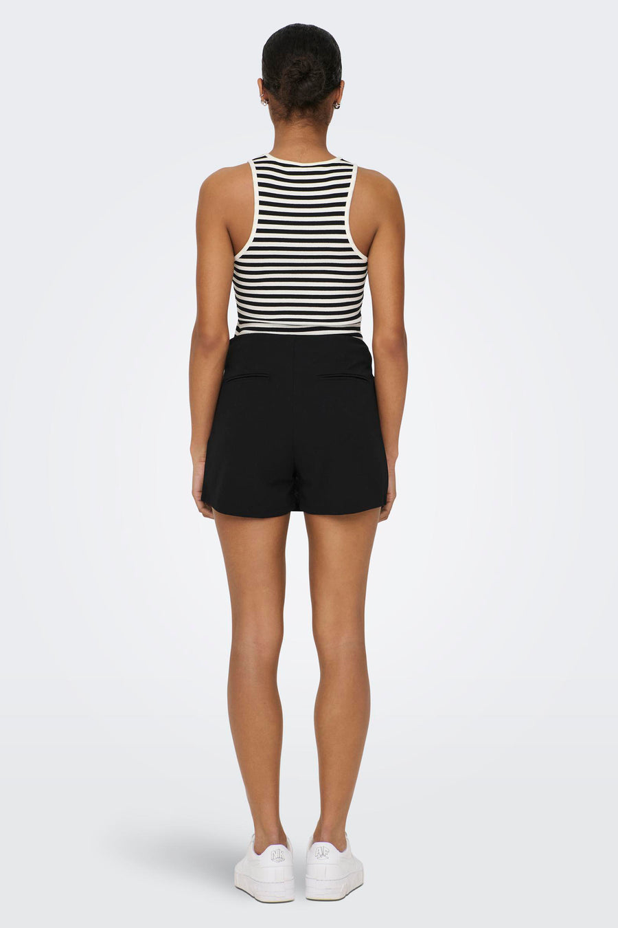 Short noir JDY, avec l'apparence d'une jupe et un short caché, combiné à une chemise rayée et des baskets blanches.