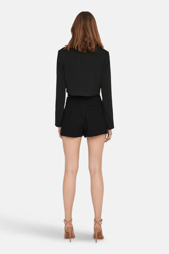 Short noir ONLY®, visible à l'arrière, associé à un blazer coordonné et des talons hauts.