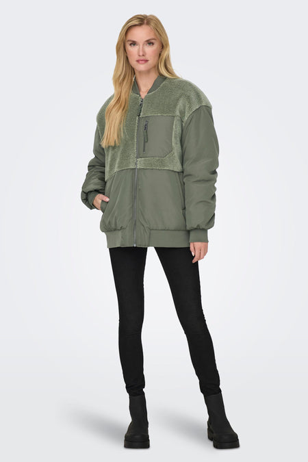 Veste verte de ONLY, avec des détails en fourrure et associée à des jeans noirs et des escarpins.