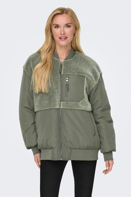 Veste verte de ONLY avec détail teddy sur les épaules et pantalon noir.