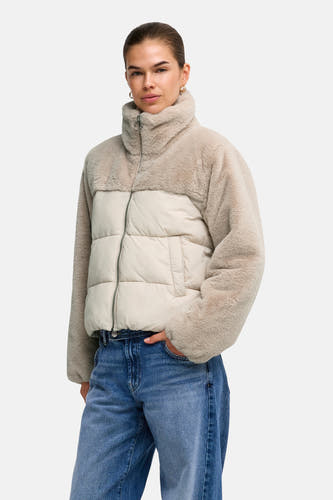 Doudoune gris clair avec manches et col en fausse fourrure teddy de la marque ONLY®, dotée d'une fermeture éclair et de poches, portée avec un jean bleu.